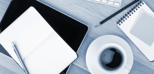 Office supplies, gadgets and coffee cup on wooden table